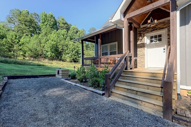 entrance to property featuring board and batten siding, covered porch, and stone siding