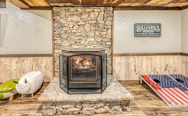 interior details with a stone fireplace, a wainscoted wall, and wood walls