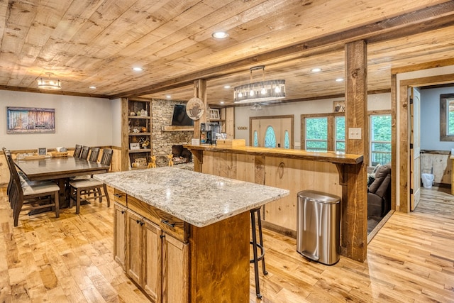 kitchen featuring light wood finished floors, a breakfast bar area, a center island, and wood ceiling