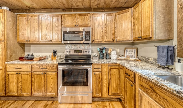 kitchen featuring stainless steel appliances, wood ceiling, brown cabinetry, and light wood finished floors