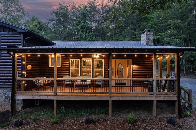 back of house at dusk featuring metal roof and a chimney