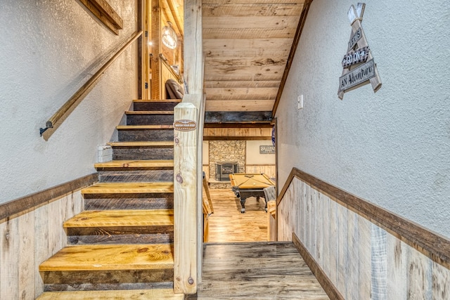 stairway with wooden ceiling, a textured wall, and wood finished floors