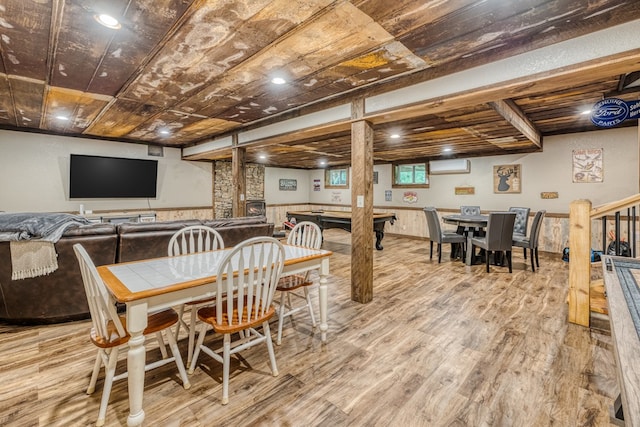 dining area featuring a wall mounted air conditioner, wainscoting, and light wood finished floors