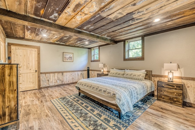 bedroom featuring wood ceiling, wood finished floors, a wainscoted wall, and wood walls