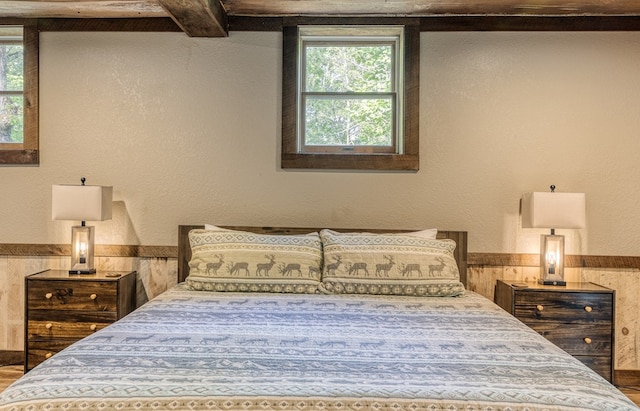 bedroom with beamed ceiling and wainscoting