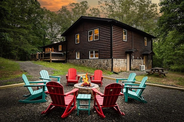 rear view of house featuring stone siding, a deck, and an outdoor fire pit