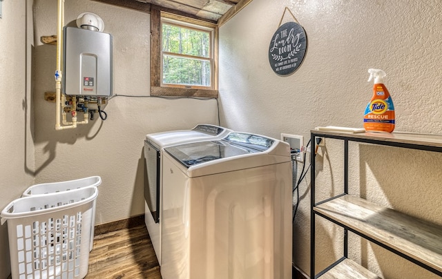 laundry room featuring washing machine and clothes dryer, a textured wall, tankless water heater, laundry area, and wood finished floors