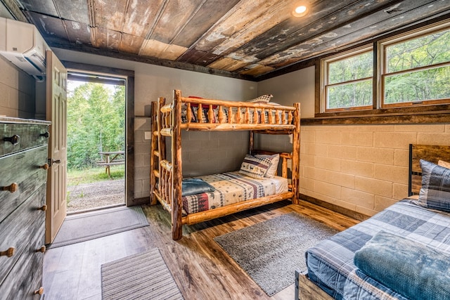 bedroom with wooden ceiling, access to outside, concrete block wall, and wood finished floors