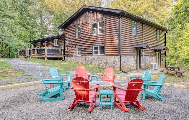 rear view of house featuring a wooden deck, stone siding, and a fire pit