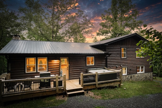 back of house featuring metal roof, a deck, and a chimney