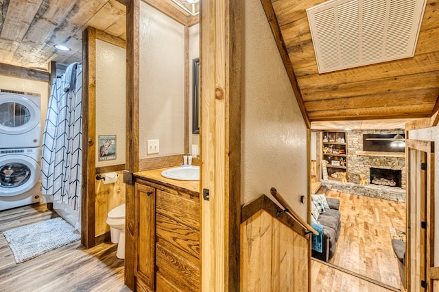 bathroom featuring built in features, wood finished floors, visible vents, stacked washer and dryer, and toilet