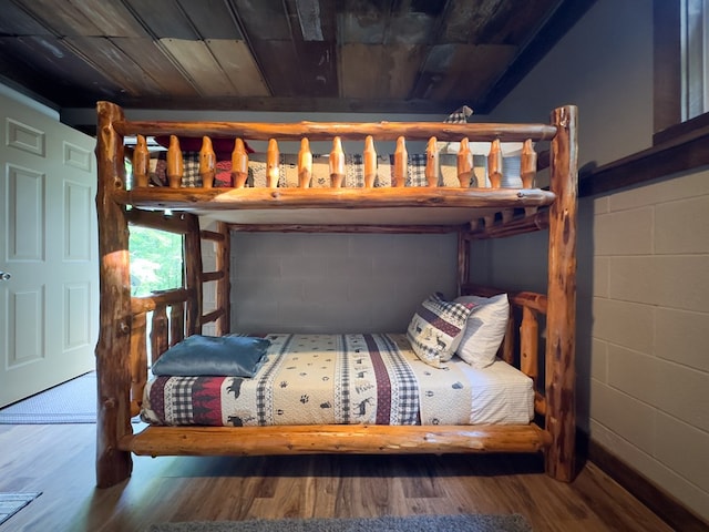 bedroom featuring wooden ceiling, concrete block wall, and wood finished floors