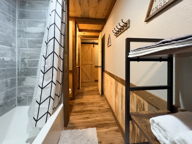 hall featuring beamed ceiling, wainscoting, wooden ceiling, and wood finished floors