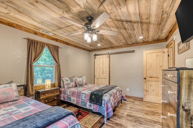 bedroom with visible vents, wood ceiling, wood finished floors, a barn door, and a textured wall