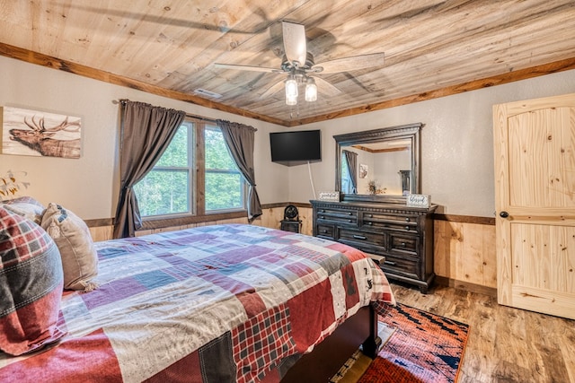 bedroom featuring a wainscoted wall, a ceiling fan, wood finished floors, wooden ceiling, and wood walls