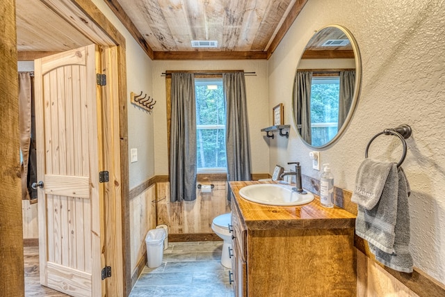 bathroom with visible vents, toilet, wood ceiling, vanity, and a textured wall