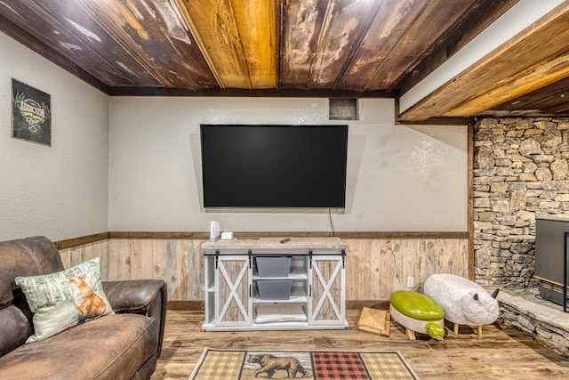 unfurnished living room featuring a wainscoted wall, wooden walls, wood ceiling, and wood finished floors