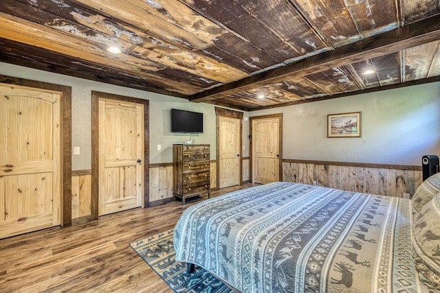 bedroom with a wainscoted wall, wood walls, wooden ceiling, and wood finished floors