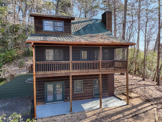 rear view of property with a patio, a sunroom, a chimney, french doors, and metal roof