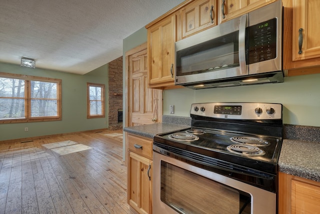 kitchen featuring dark countertops, light wood finished floors, appliances with stainless steel finishes, and a textured ceiling