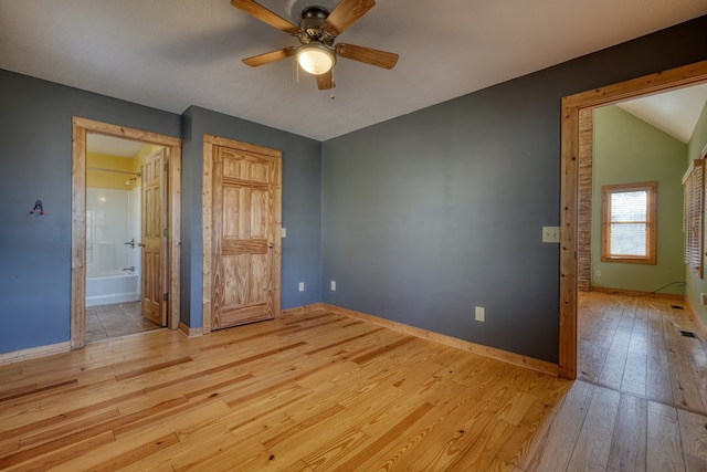 unfurnished bedroom with a ceiling fan, baseboards, vaulted ceiling, wood-type flooring, and connected bathroom