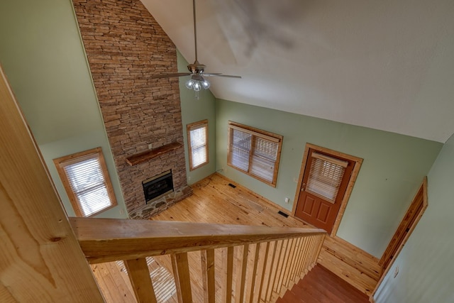 stairs featuring a wealth of natural light, a fireplace, a ceiling fan, and wood finished floors