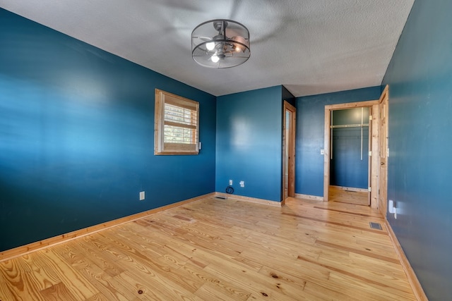 unfurnished bedroom featuring a closet, visible vents, baseboards, and wood finished floors