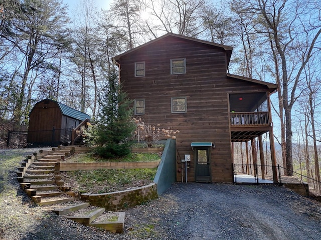 rear view of property with gravel driveway, a barn, and an outbuilding