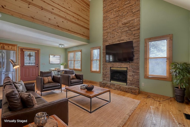 living area featuring a wealth of natural light, a high ceiling, hardwood / wood-style floors, and a fireplace