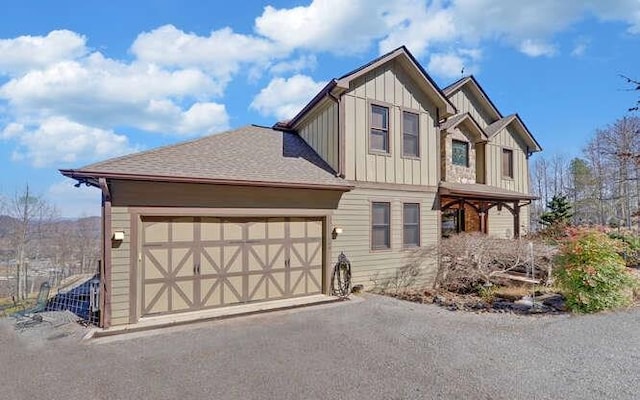 view of front facade featuring board and batten siding, an attached garage, and aphalt driveway