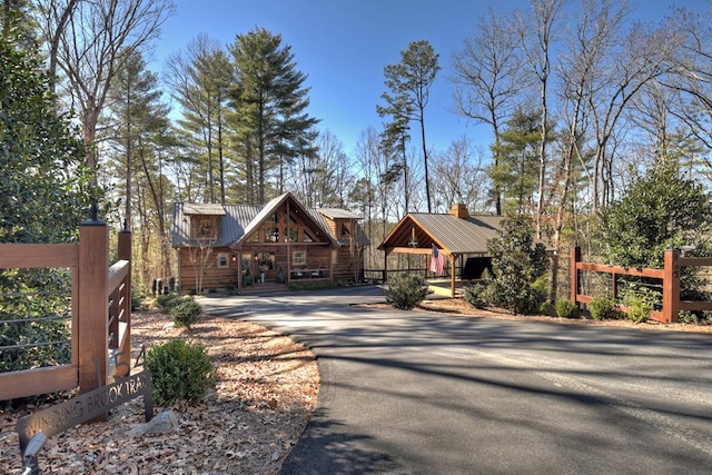 view of front of house featuring aphalt driveway, metal roof, and fence