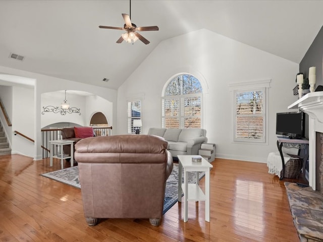 living room featuring ceiling fan with notable chandelier, wood-type flooring, and high vaulted ceiling