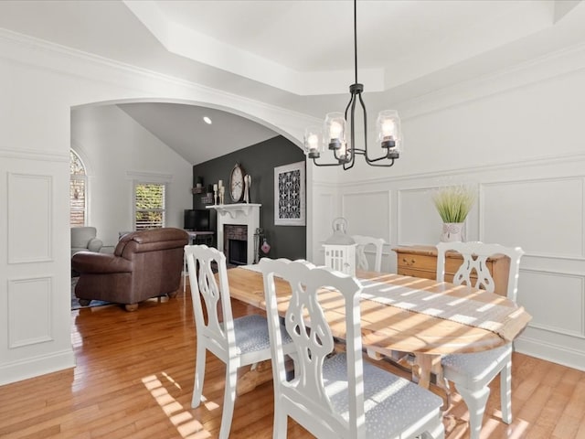 dining space featuring light hardwood / wood-style flooring, a raised ceiling, and a chandelier