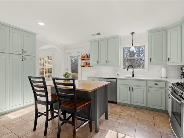 kitchen featuring sink, crown molding, appliances with stainless steel finishes, tasteful backsplash, and decorative light fixtures