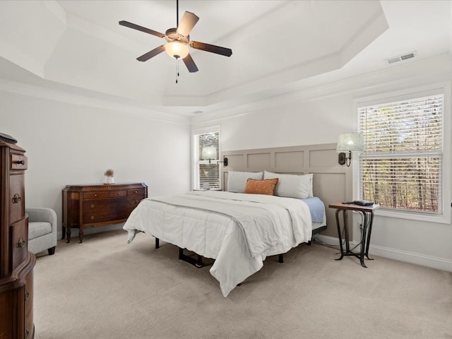 bedroom featuring light carpet, crown molding, a raised ceiling, and ceiling fan