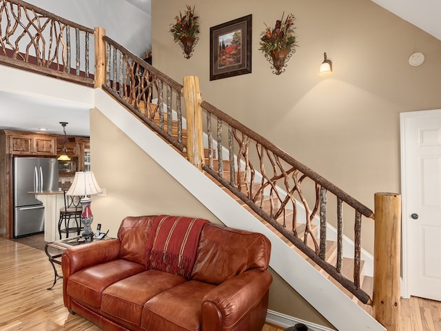 staircase featuring high vaulted ceiling and wood-type flooring