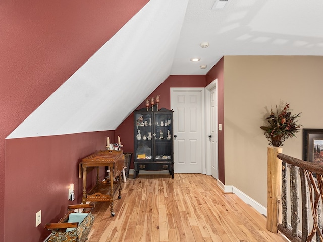 hall with light hardwood / wood-style flooring and vaulted ceiling