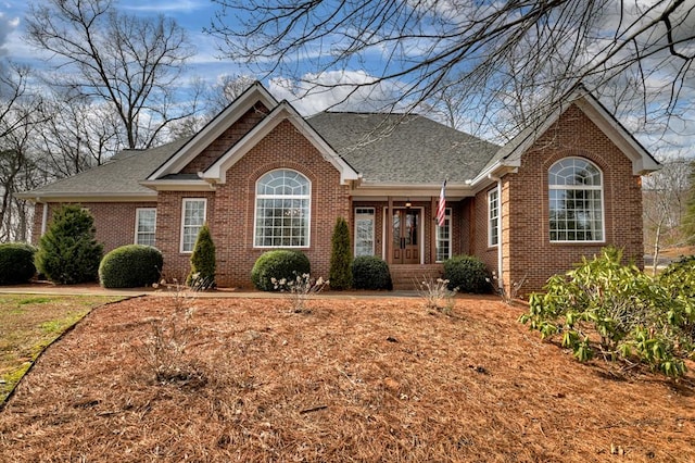 view of front of property featuring a shingled roof and brick siding