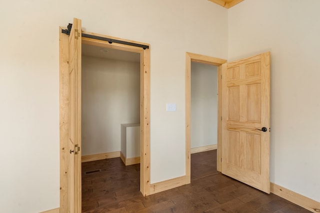 unfurnished bedroom featuring dark wood-style floors, visible vents, and baseboards