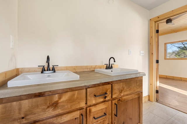 full bath with double vanity, marble finish floor, baseboards, and a sink