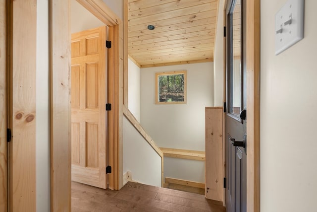 hallway with wood ceiling, wood finished floors, and an upstairs landing