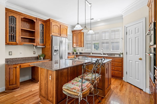 226 Euharlee Five Forks Rd, Kingston, GA 30145 - kitchen featuring appliances with stainless steel finishes, brown cabinets, ornamental molding, a kitchen island, and glass insert cabinets