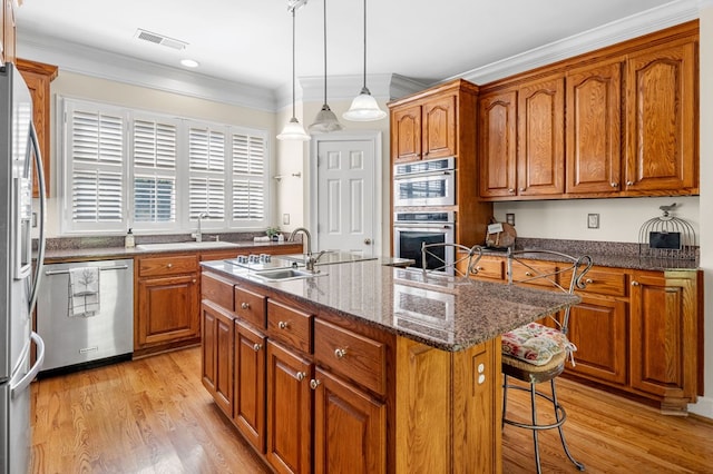 226 Euharlee Five Forks Rd, Kingston, GA 30145 - kitchen with appliances with stainless steel finishes, a sink, brown cabinets, a breakfast bar area, and light wood-style floors