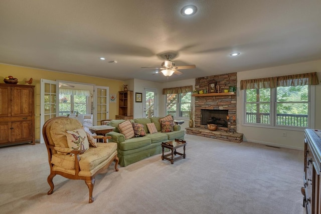 living room with a fireplace, ceiling fan, a textured ceiling, and light carpet