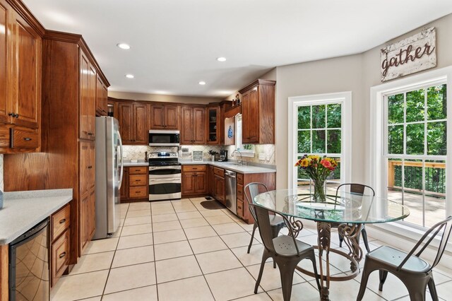 kitchen featuring backsplash, sink, light tile patterned floors, appliances with stainless steel finishes, and beverage cooler