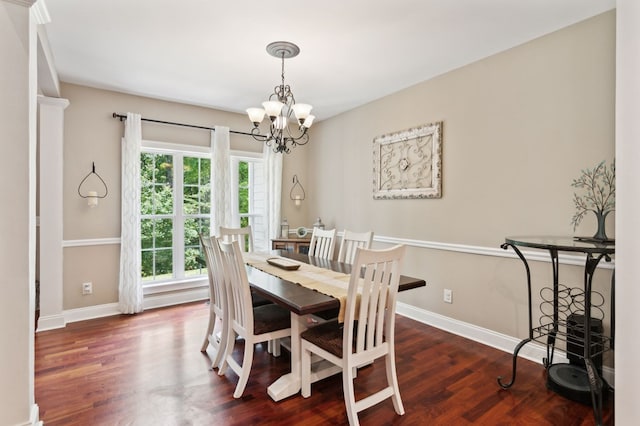 dining area with dark wood-type flooring and an inviting chandelier