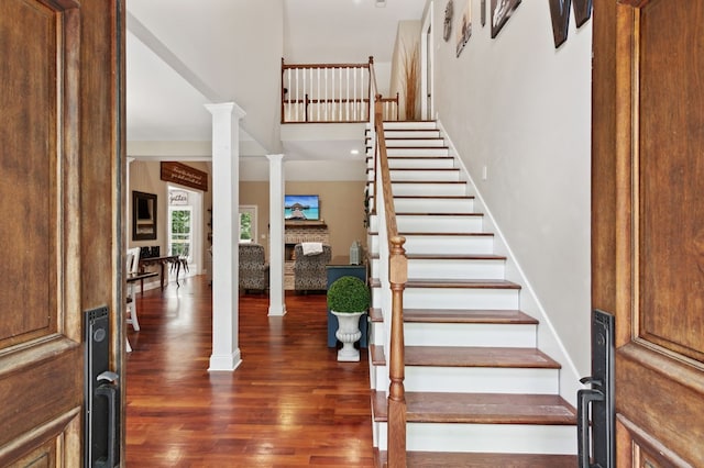 entryway featuring dark hardwood / wood-style flooring, ornate columns, and a fireplace