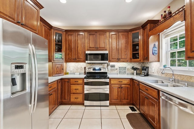 kitchen featuring backsplash, sink, light tile patterned floors, and stainless steel appliances