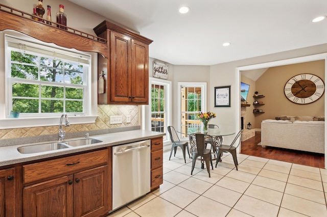 kitchen with stainless steel dishwasher, plenty of natural light, light hardwood / wood-style floors, and sink