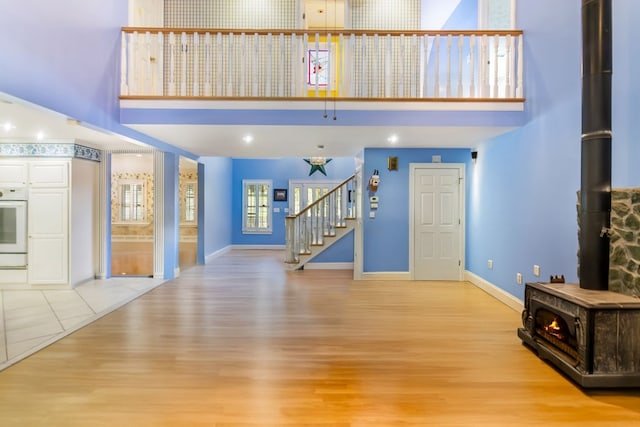 unfurnished living room with a wood stove, light hardwood / wood-style flooring, and a high ceiling